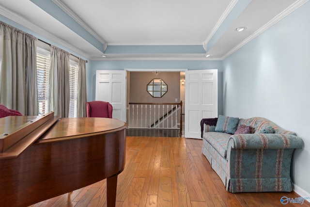 interior space featuring ornamental molding, a raised ceiling, baseboards, and hardwood / wood-style floors