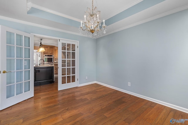 unfurnished room with a tray ceiling, french doors, and dark wood-type flooring