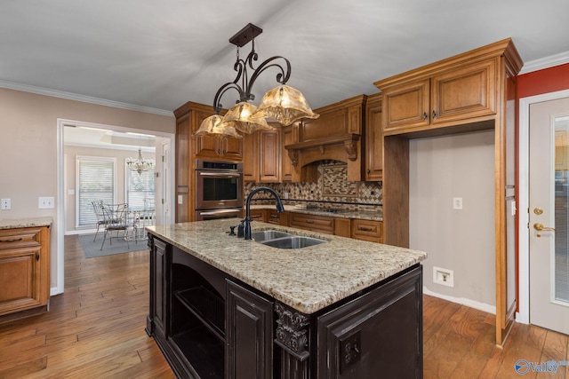 kitchen with double oven, ornamental molding, dark wood-type flooring, and a sink