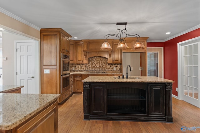 kitchen with crown molding, double oven, light wood-type flooring, brown cabinets, and a sink