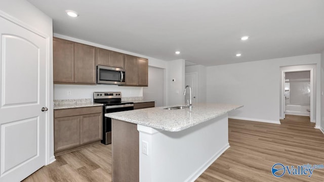 6156 Feather Way SE, Owens Cross Roads, AL 35763 - kitchen featuring appliances with stainless steel finishes, a sink, light wood-type flooring, baseboards, and an island with sink