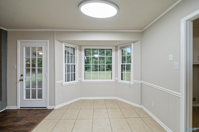 interior space featuring crown molding, tile patterned floors, and baseboards