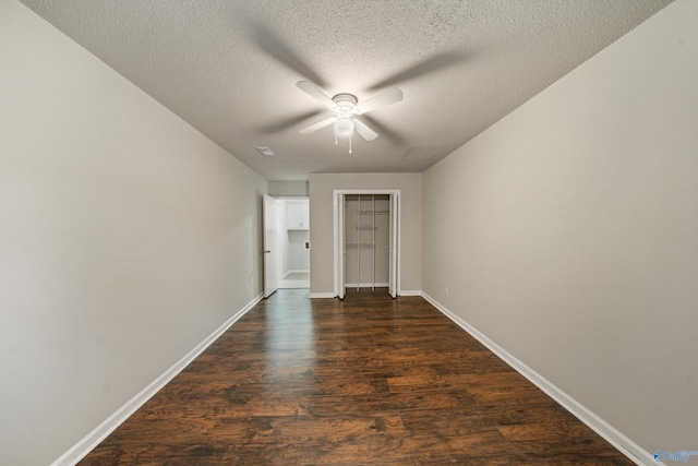 unfurnished bedroom featuring a textured ceiling, a ceiling fan, baseboards, dark wood-type flooring, and a closet