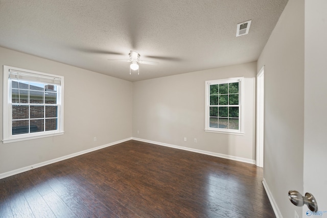 unfurnished room with visible vents, dark wood-type flooring, ceiling fan, and a healthy amount of sunlight