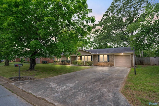 ranch-style home with a yard, brick siding, fence, concrete driveway, and an attached garage