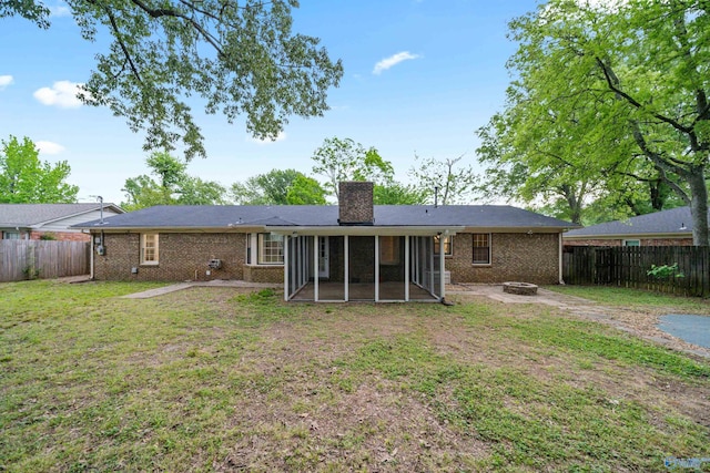 rear view of property with a fire pit, a fenced backyard, a sunroom, and a chimney