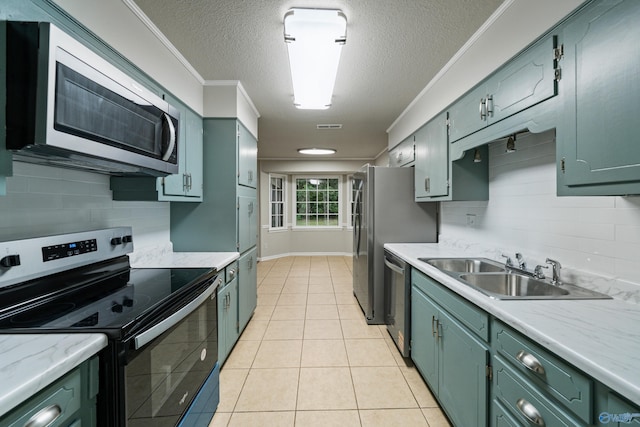 kitchen featuring a textured ceiling, appliances with stainless steel finishes, a sink, and green cabinetry