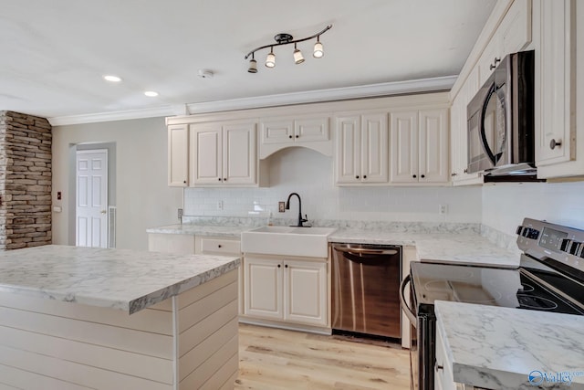 kitchen with backsplash, ornamental molding, stainless steel appliances, sink, and light hardwood / wood-style flooring