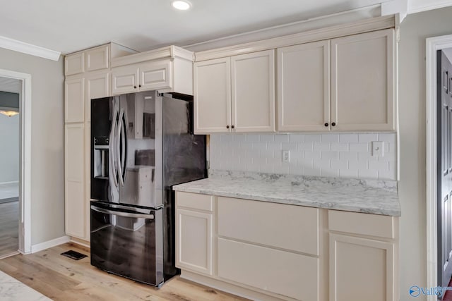 kitchen featuring light stone countertops, stainless steel refrigerator with ice dispenser, light wood-type flooring, tasteful backsplash, and crown molding