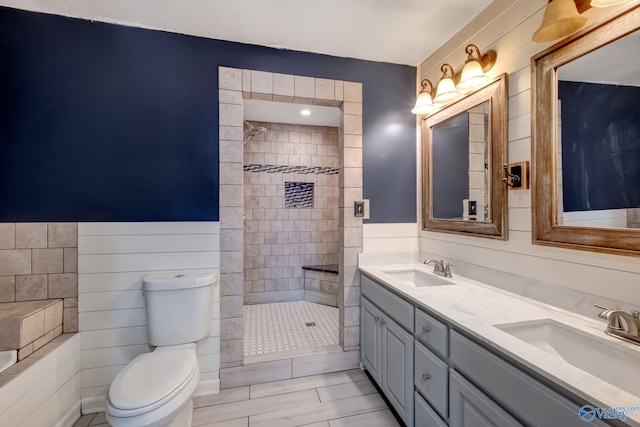 bathroom featuring a tile shower, vanity, and toilet