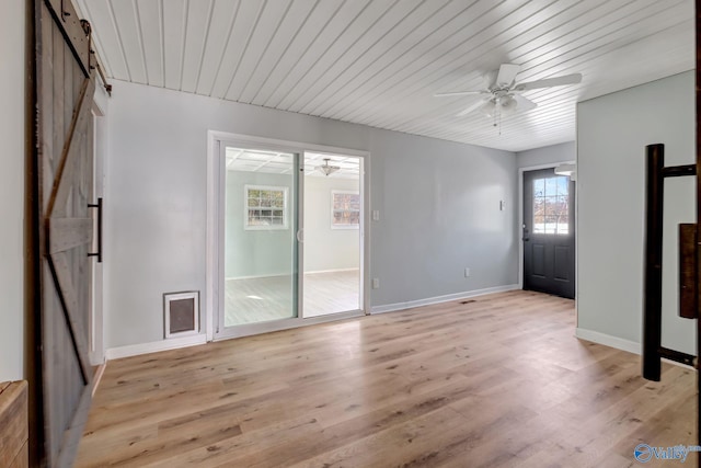 interior space with a barn door, ceiling fan, light hardwood / wood-style flooring, and wood ceiling