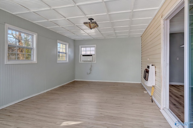 interior space featuring cooling unit, wood walls, light wood-type flooring, and heating unit