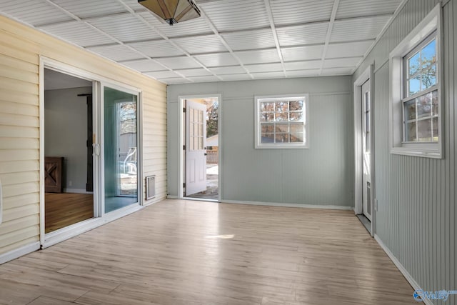 unfurnished room featuring wood walls and light hardwood / wood-style floors