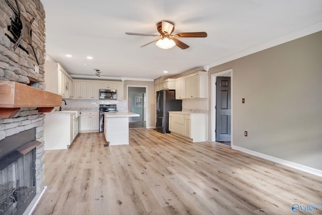 kitchen featuring crown molding, a fireplace, light hardwood / wood-style floors, and appliances with stainless steel finishes