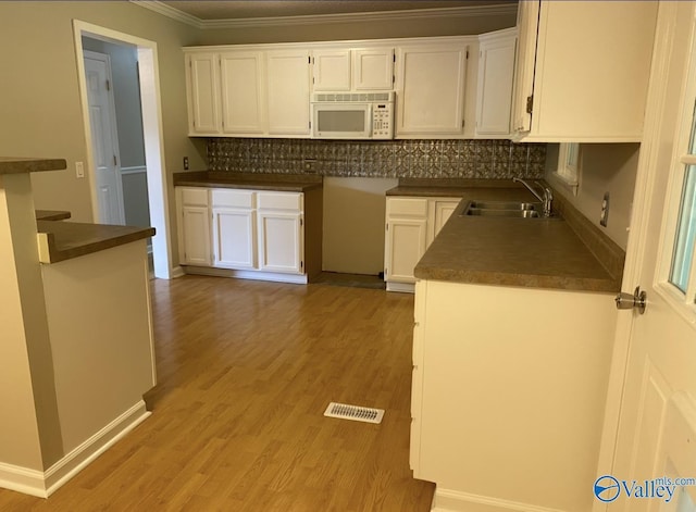 230 Hampton Rd, Hartselle, AL 35640 - kitchen featuring white microwave, ornamental molding, a sink, decorative backsplash, and white cabinets