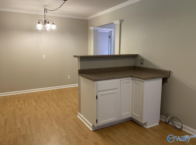 230 Hampton Rd, Hartselle, AL 35640 - kitchen with dark countertops, light wood-type flooring, white cabinets, crown molding, and a chandelier