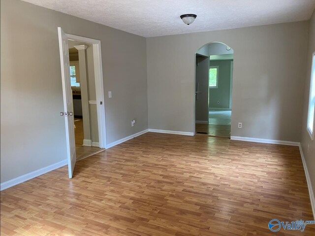 230 Hampton Rd, Hartselle, AL 35640 - spare room featuring arched walkways, light wood-style flooring, a textured ceiling, and baseboards