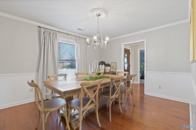 dining space featuring hardwood / wood-style floors, an inviting chandelier, and ornamental molding