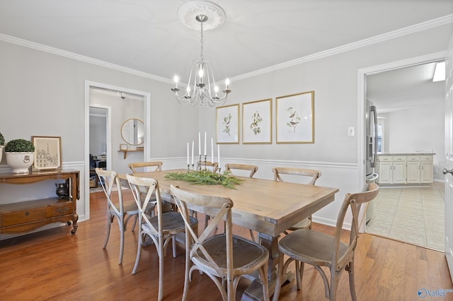 dining area with light hardwood / wood-style flooring, a chandelier, and ornamental molding