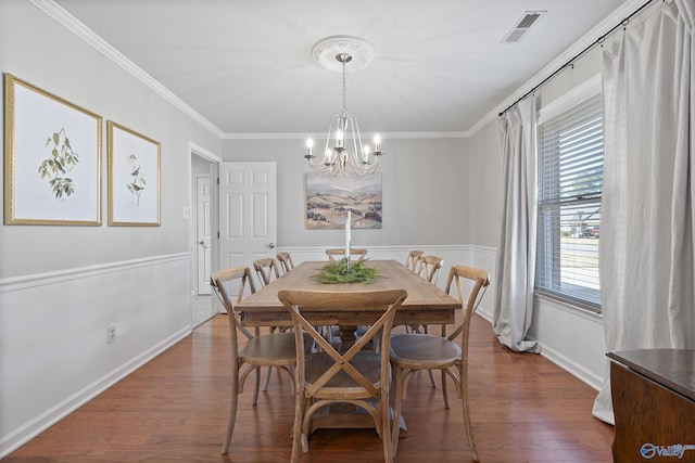 dining space featuring crown molding, dark wood-type flooring, and an inviting chandelier