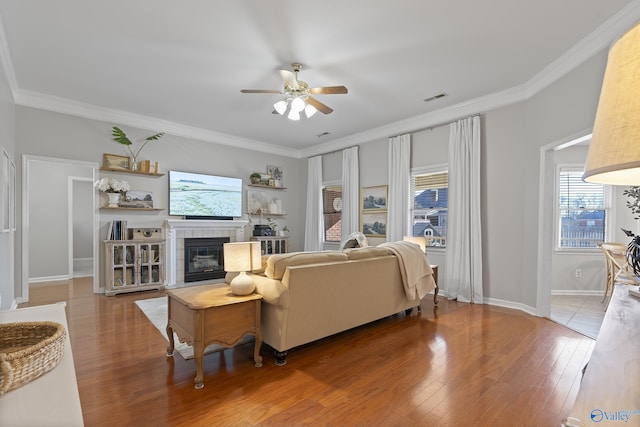 living room featuring hardwood / wood-style floors, ornamental molding, and a tiled fireplace
