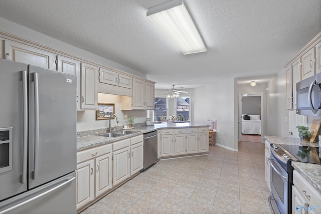 kitchen featuring cream cabinets, sink, ceiling fan, light tile patterned floors, and appliances with stainless steel finishes