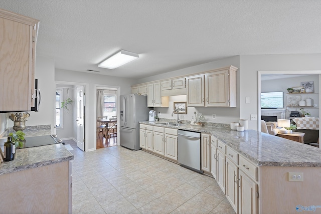 kitchen with sink, light tile patterned floors, a textured ceiling, stainless steel appliances, and a tiled fireplace
