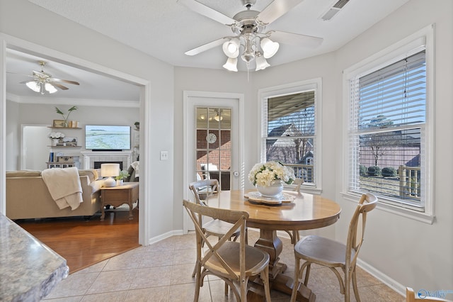 dining room with a fireplace, light tile patterned floors, a textured ceiling, and ceiling fan