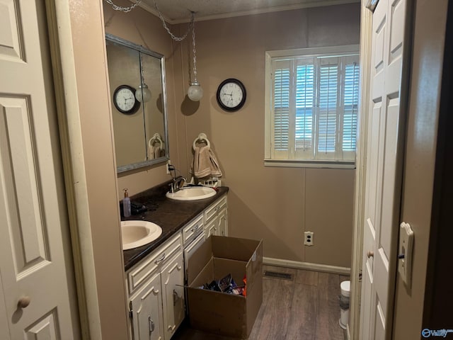 bathroom featuring double vanity, visible vents, a sink, and wood finished floors