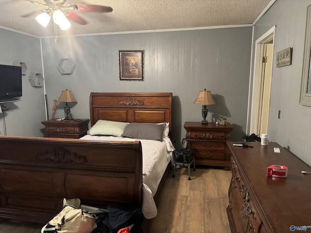 bedroom featuring a textured ceiling, ornamental molding, wood finished floors, and a ceiling fan