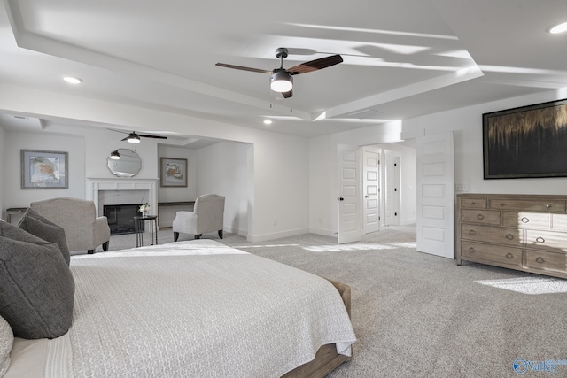 bedroom with a raised ceiling, ceiling fan, and light colored carpet