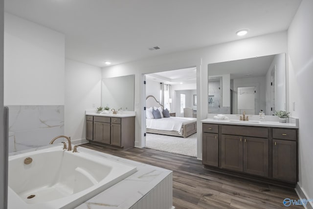 bathroom featuring vanity, wood-type flooring, and tiled bath