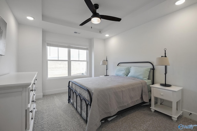 carpeted bedroom with a raised ceiling and ceiling fan