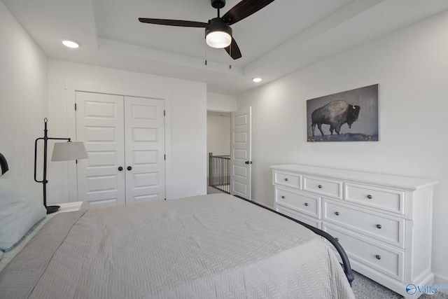 bedroom with ceiling fan, a raised ceiling, and a closet