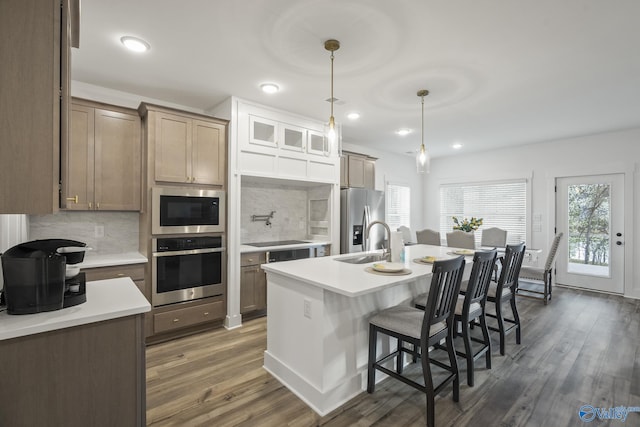 kitchen featuring decorative backsplash, stainless steel appliances, sink, a center island with sink, and dark hardwood / wood-style floors