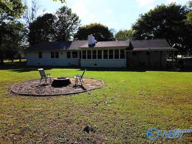 rear view of house with a fire pit and a yard