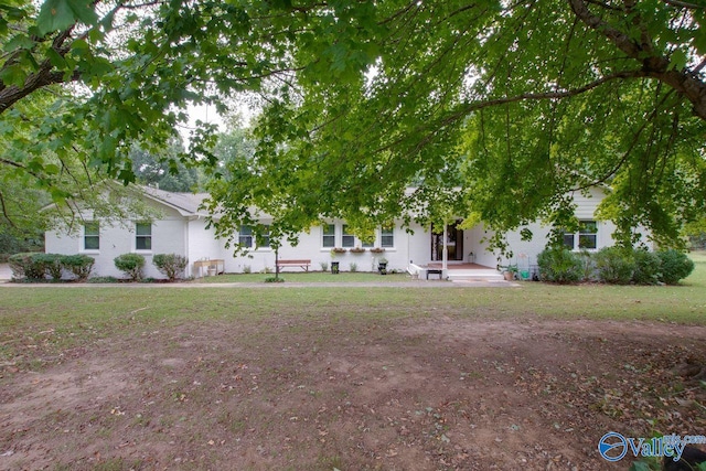 view of property hidden behind natural elements featuring a front lawn