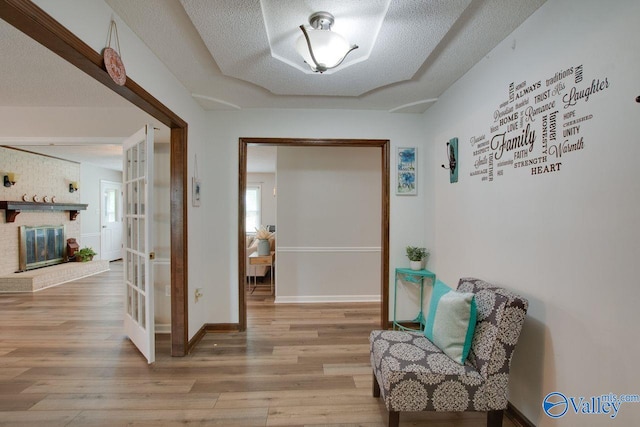 sitting room with a textured ceiling, wood-type flooring, and a brick fireplace