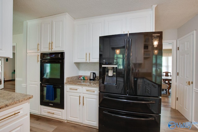 kitchen featuring black appliances, hardwood / wood-style flooring, light stone countertops, and white cabinets