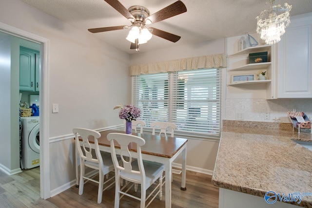 dining room with washer / clothes dryer, light hardwood / wood-style flooring, ceiling fan with notable chandelier, and a textured ceiling