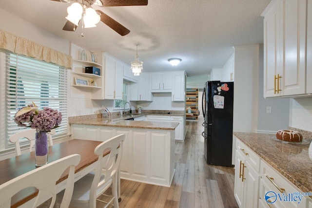 kitchen featuring light wood-type flooring, a textured ceiling, decorative light fixtures, ceiling fan, and black fridge