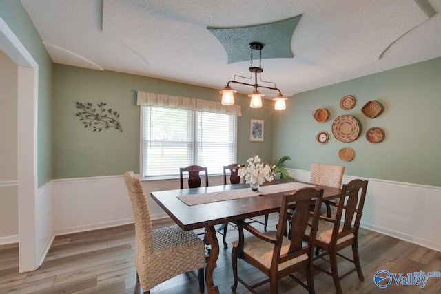 dining room featuring a textured ceiling, wood-type flooring, and a chandelier