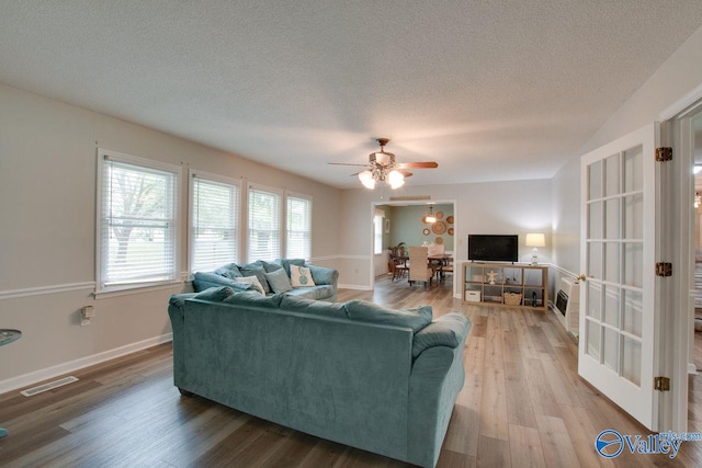 living room featuring a textured ceiling, ceiling fan, and wood-type flooring