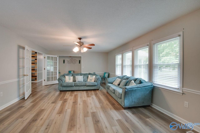 living room featuring a textured ceiling, ceiling fan, wood-type flooring, and french doors