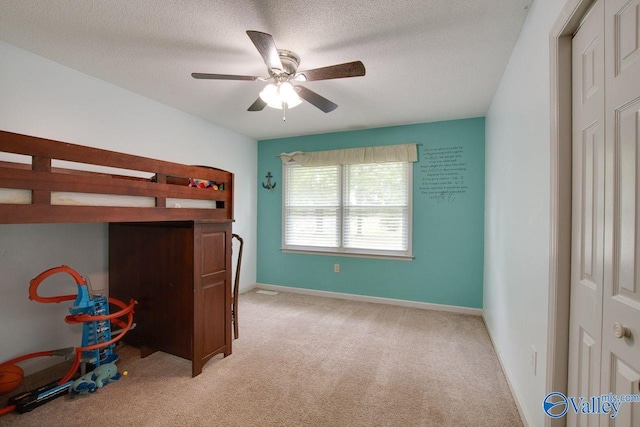 bedroom featuring light carpet, a textured ceiling, and ceiling fan