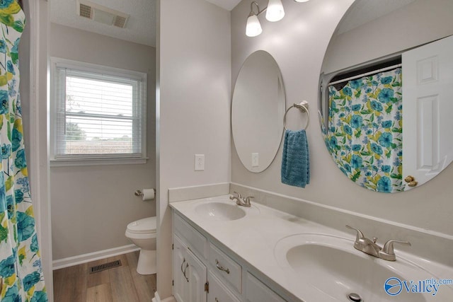 bathroom featuring a textured ceiling, vanity, toilet, and hardwood / wood-style floors