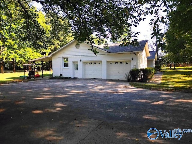 view of side of property with a garage, a yard, and a carport