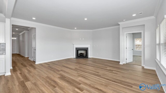 unfurnished living room with light wood-type flooring and crown molding