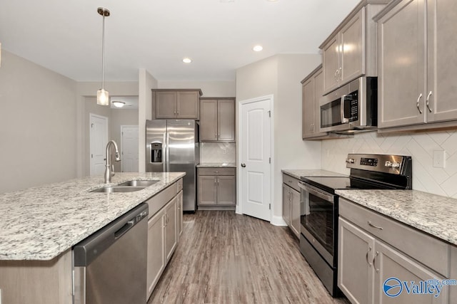 114 Burdine St, New Market, AL 35761 - kitchen with stainless steel appliances, a sink, wood finished floors, decorative backsplash, and light stone countertops