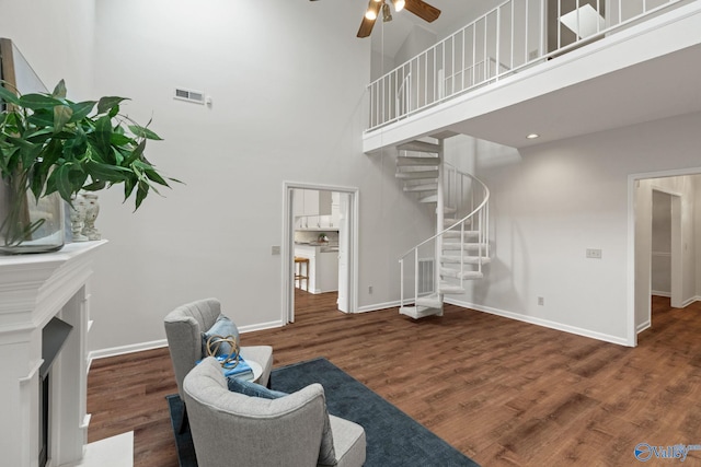 living room with ceiling fan, dark wood-type flooring, and a high ceiling